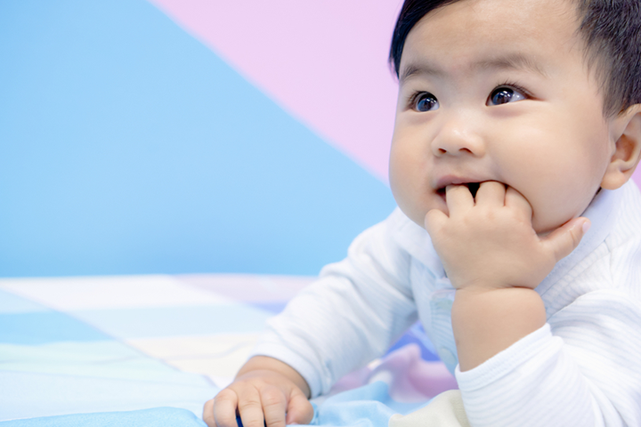 Infant putting hand in 2024 mouth